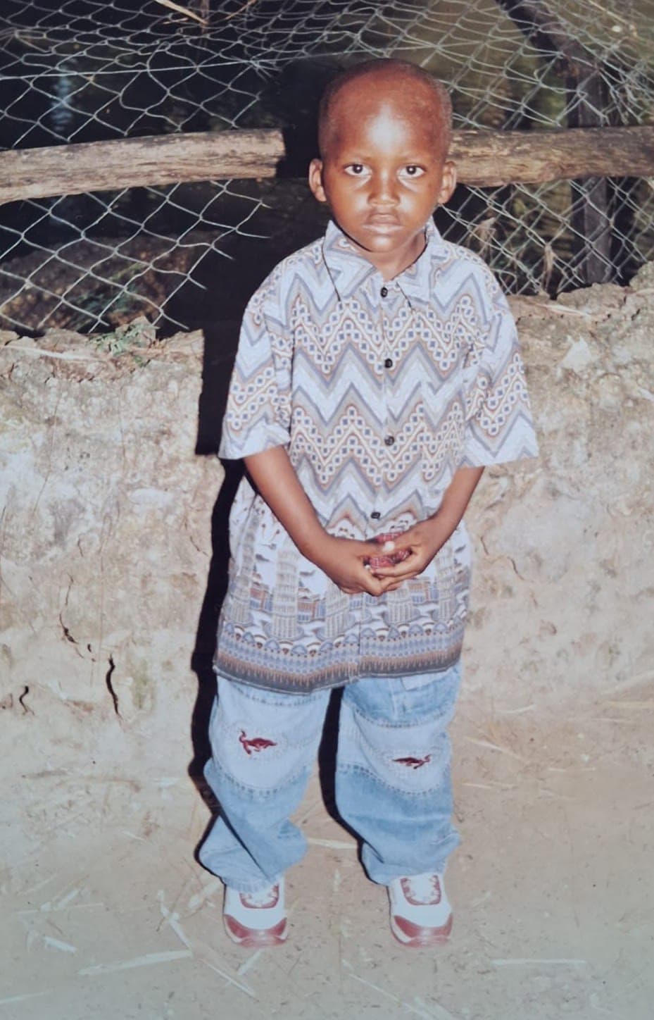 Jackson as a young boy, standing outdoors in a patterned shirt and jeans.